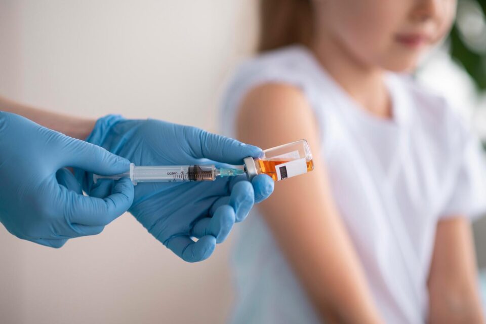 Operatore sanitario che prepara un vaccino per una bambina, a sottolineare come l'immunizzazione sia il primo passo per una cultura della prevenzione per ogni generazione